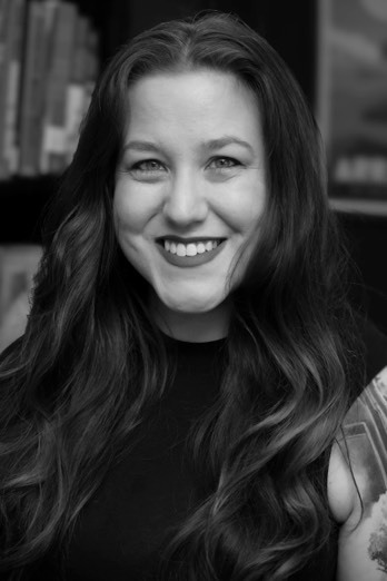 Black and white photo of author Alana Kay in front of a bookshelf