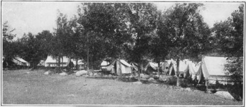 Between Wood and Field. Arrangement of wall tents with flys, set up with stakes.