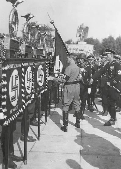 Adolf Hitler bei der Fahnenweihe in der Luitpoldarena auf dem Reichsparteitag 1934. Hitler ber¸hrt dabei mit der Fahne des Hitlerputsches von 1923, der sogenannten Blutfahne, neue Standarten, darunter die von Heilbronn.