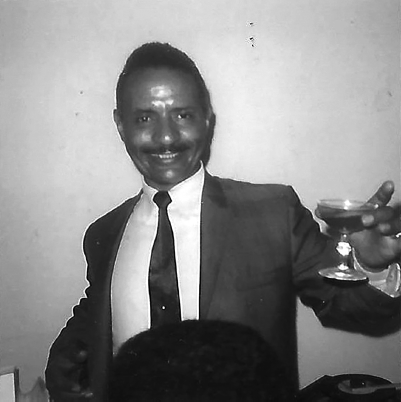 A photo of Harvey Williams smiling and raising a toast.