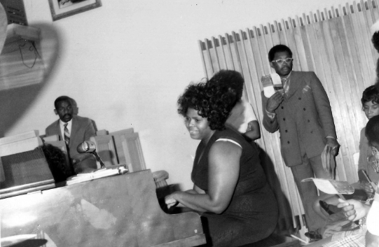 A photo of Gertrude Hicks playing the piano at an event.