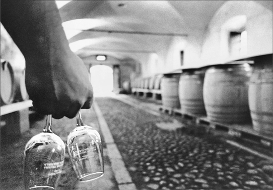 A man carring two wine glasses upside down through a cellar