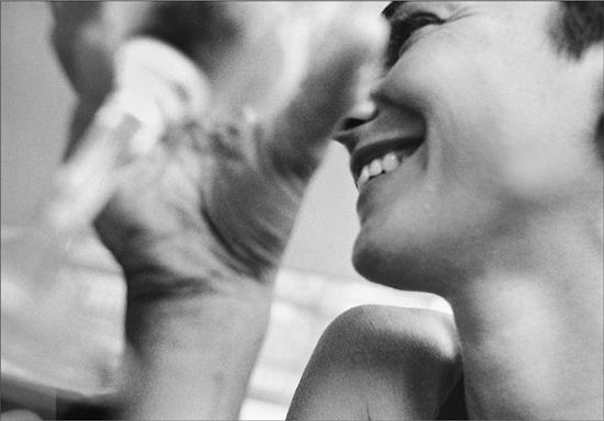 A woman smiling and drinking a glass of wine