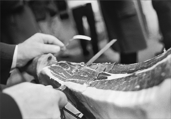 A man slicing paper-thin slices of prosciutto