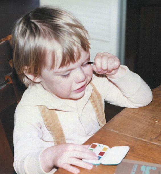 Toddler applying eye makeup clumsily, in an imitation of its mother.