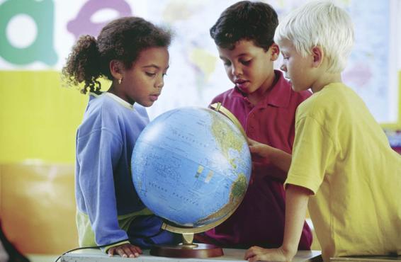 Photo of three children in a classroom examining a globe.