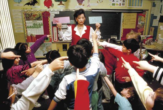 Photo of a bilingual classroom, where the teacher is using homemade flashcards to engage all students.