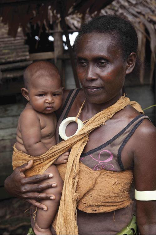 Photo of a father interacting with his baby: holding his arms while talking and laughing close to his face and maintaining eye contact.