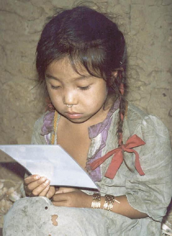 Photo of a young Asian girl looking at a paper or photo.