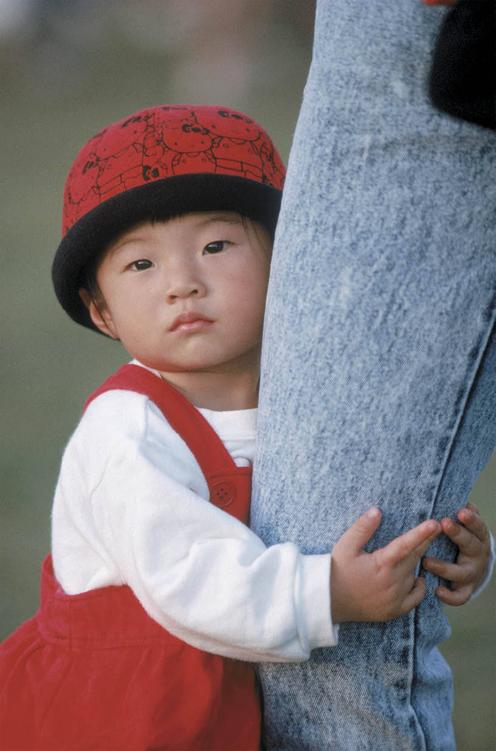 Photo of toddler clinging to adult’s leg.