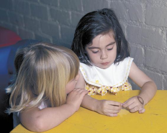 Photo of one little girl trying to comfort another by touching her arm.