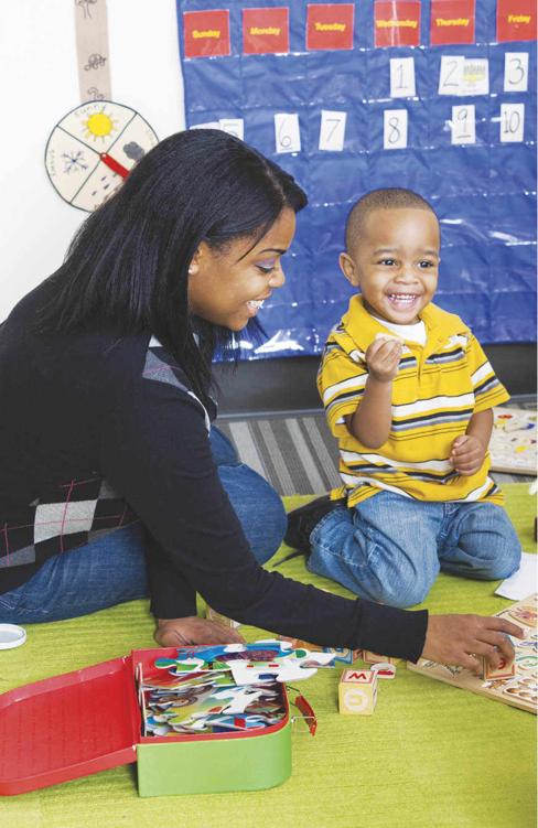 Photo of a childcare worker and a child playing a puzzle-like game.