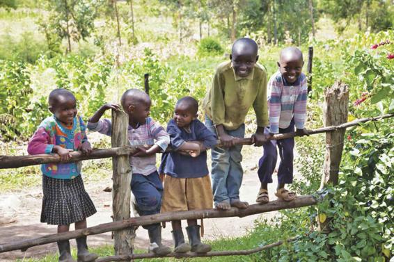 Photo of five Kenyan children laughing together as they play on a fence.