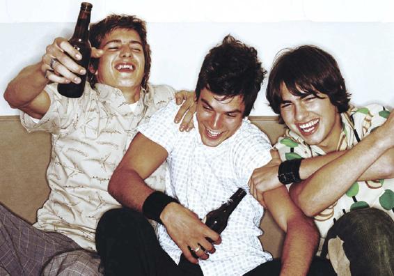 Photo of three young men laughing as they drink beer.