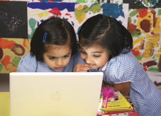 Photo of two young girls deeply interested in something they are viewing on a computer.