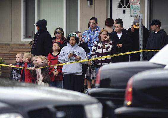 Photo of a crowd of mostly males standing behind crime-scene tape, watching an event.