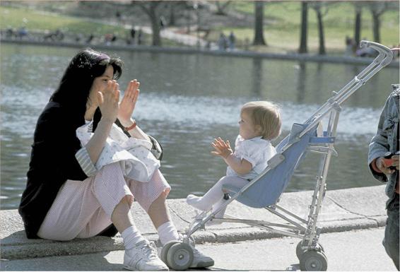 Photo of an adult and baby. The adult is clapping her hands and the baby is imitating the action.