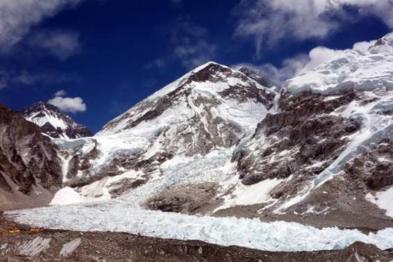 The approach to Everest Base Camp. The yellow tents of Base Camp can be seen front left. Changtse is the rock peak back left. The Lho La is the pass in front of it. The main triangular peak in the photo is Everest's West Shoulder. The black summit of Everest can be seen peeping up behind the West Shoulder. The peak on the right is a shoulder of Nuptse. The Khumbu Icefall spills down the gap between the West Shoulder and Nuptse.