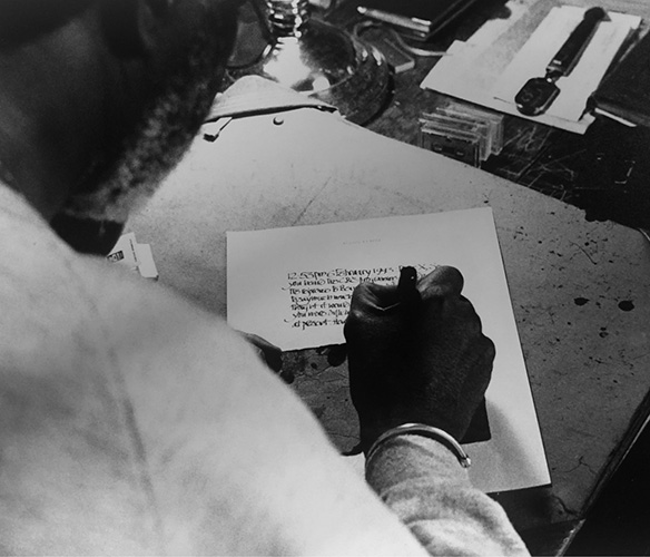 Photograph of Austin Clarke writing a letter.