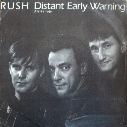 The sleeve for the single 'Distant Early Warning.' It features a black-and-white close-up group portrait of the band members. From left to right, Alex, Neil, and Geddy.