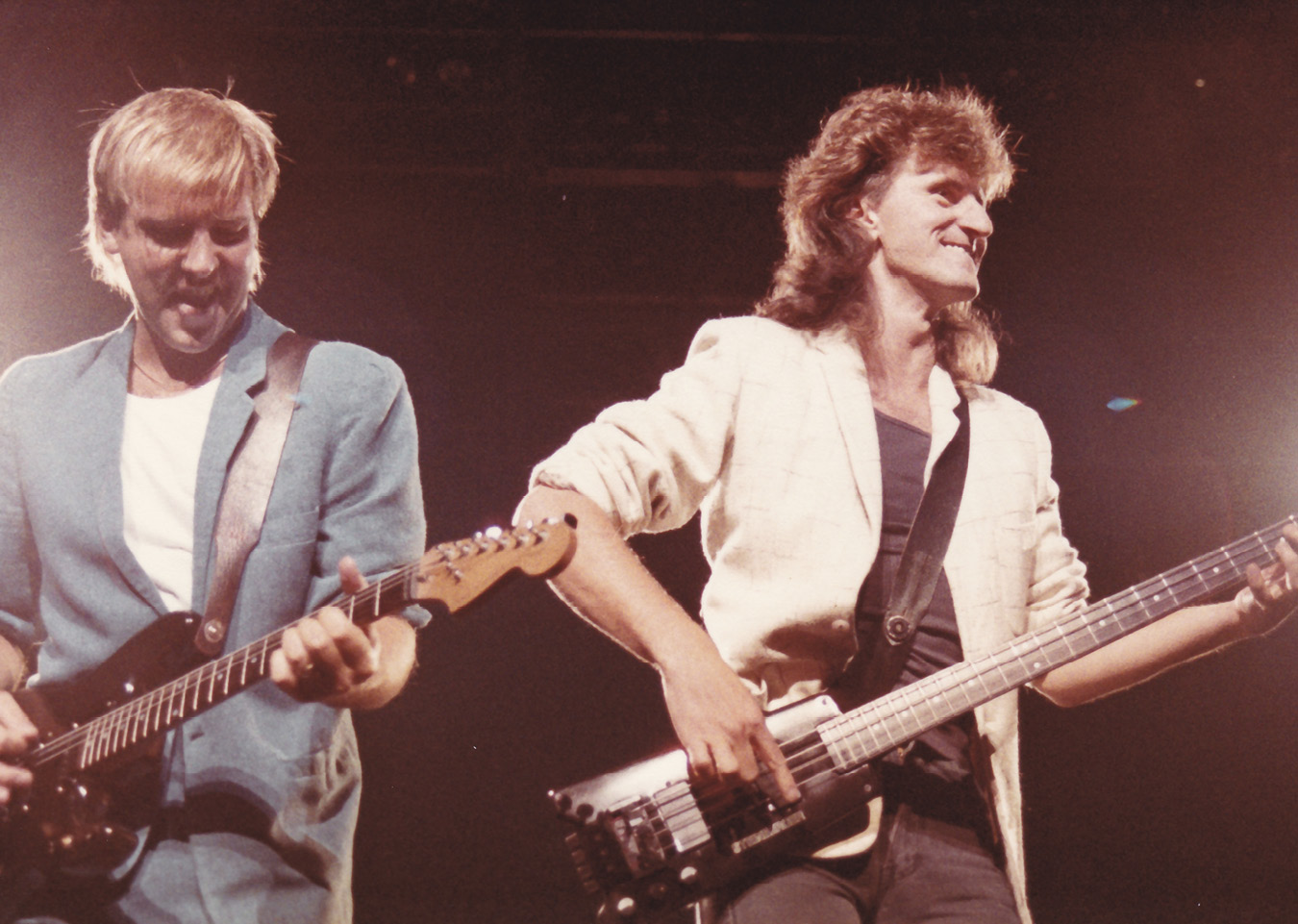 Alex, on the left, and Geddy, to the right, smile as they both play their guitars.