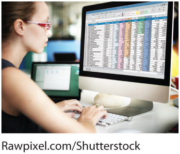 A photo shows a young woman working on a spreadsheet on her desktop. 