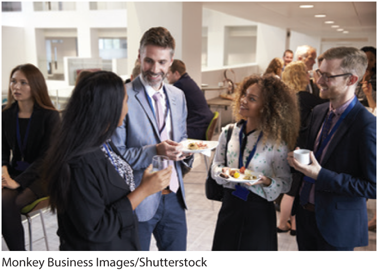 A photo shows a group of people holding refreshments and conversing at an official event.