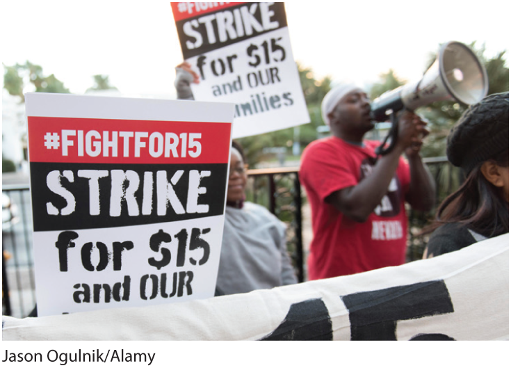 A photo shows fast food workers holding placards reading, ‘Strike: Fight for 15 dollars’ in a rally. 