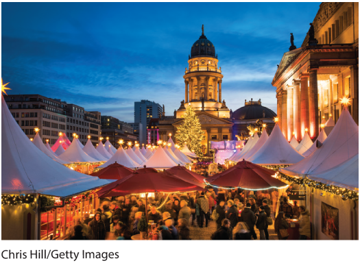 A photo shows an avenue of Christmas market tents lit up in the evening along the streets before the French Cathedral and Berlin Cathedral in Berlin.