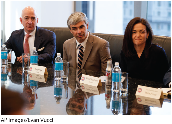 A photo shows Jeff Bezos, Larry Page, and Sheryl Sandberg seated at a meeting. 