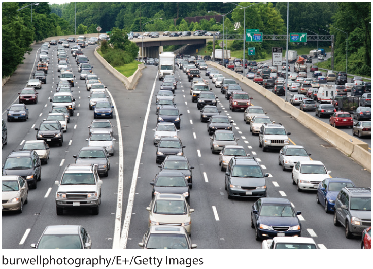 A photo shows a multitude of cars plying on a two-way road that leads to three different directions.