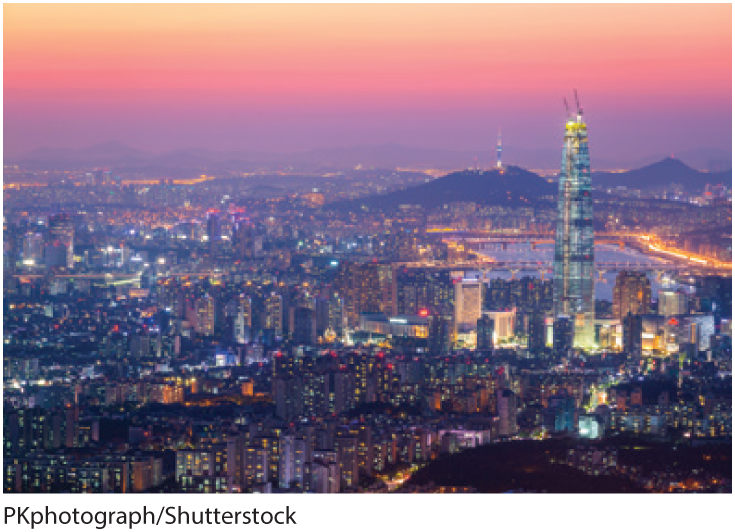 A photo shows an aerial view of a city with many skyscrapers in South Korea during dusk.