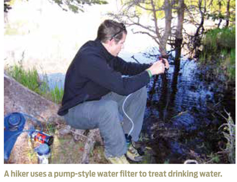 A hiker uses a pump-style water filter to treat drinking water