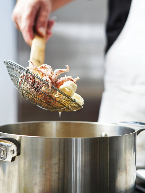 Lowering breaded calamari into a pot of oil