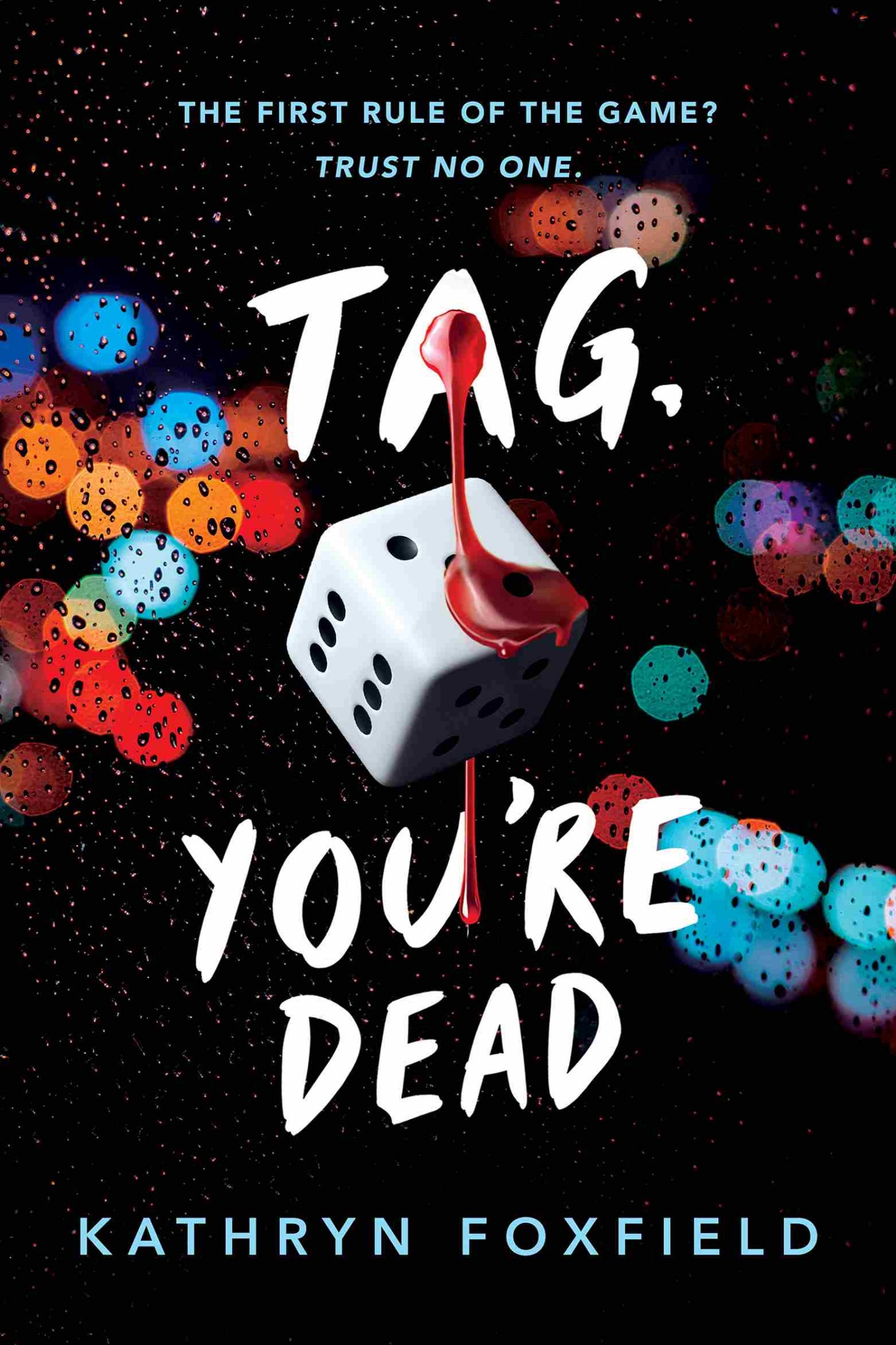 Front cover for Tag, You're Dead by Kathryn Foxfield. Background includes a die with blood dripping on it, and an abstract design on the background with droplets and dots of light. 