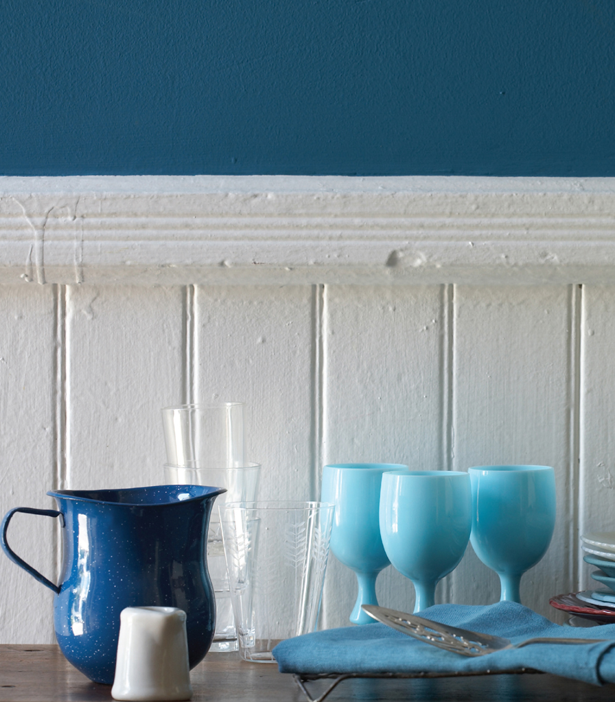 A blue pitcher with assorted colorful plates and glassware