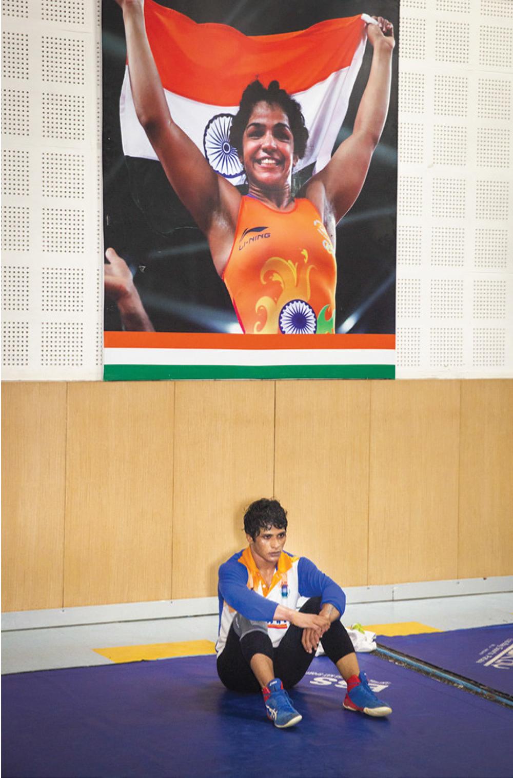 Un’atleta al Sir Chhotu Ram stadium sotto la foto della campionessa olimpica Sakshi Malik, vincitrice del bronzo olimpico a Rio nel 2016 ed ex allieva della scuola.